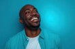 © andyaziz6 - Joyful black man wearing a turquoise shirt smiling against bright blue background