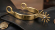 © INDI - A gold western spur on a saddle.