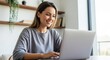 © DesignAIPro - Happy young woman working on laptop at home office