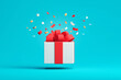© Henry Saint John - White gift box with red ribbon opening and confetti flying on blue background