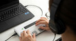 © fitria - A person wearing headphones uses a braille display connected to a laptop, demonstrating assistive technology for the visually impaired.