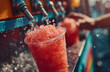 © Jack - Red slushy drink poured from a colorful machine into a clear plastic cup. Hands pull lever on dispenser creating icy, juicy summer refreshment. Carnival beverage.