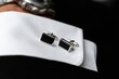 © whitestorm - Elegant rectangular black onyx cufflinks with silver trim resting on a crisp white shirt cuff, luxury accessory