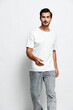 © SHOTPRIME STUDIO - Full body smiling young man wearing a white t-shirt and gray pants, looking at the camera with a friendly expression, isolated on a light background. People lifestyle concept.