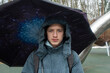 © Ruslan Russland - Serious teenage boy under galaxy print umbrella in rain