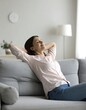 © Dafi - A woman relaxing on a couch with her hands behind her head