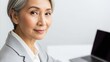 © Photo Moon - Professional Asian businesswoman with silver hair smiling while working on laptop computer in modern office environment
