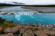 © NZstockphoto - View of rapids and turquoise coloured water with red lichen covered rocks in the foreground