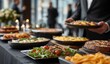 © Alexei - Business event featuring elegantly arranged buffet with various dishes, including salads, pasta, and desserts, attended by individuals in suits in a modern indoor setting