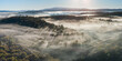 © Austockphoto - Aerial panorama view of rays of light through fog over a forested valley and distant hills