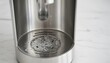© antuanetto - Close up of the stainless steel surface while cleaning the inside of a hot water dispenser for hygiene maintenance concept with bubbling water for household appliance care