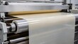 © DigitalSpace - Film label stock moving through a highspeed wide web coater receiving a uniform layer of pressuresensitive adhesive for flexible durable label production.