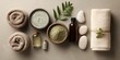 © Ketsaratchaya - Tranquil Spa Essentials for a Relaxing Experience with Towels, Natural Oils, Clay Mask, Pebbles, and Greenery on a Minimalist Background