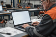 © starush - Man using laptop in industrial workshop with technical drawings on table