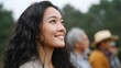 © Bussakon - A smiling young woman viewed in profile at an outdoor gathering suggesting joy and connection with family and friends