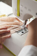 © Viktoriya Savinkova - A close-up photo of a seamstress sewing beige lace on a sewing machine. Photo grain added.