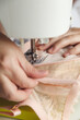 © Viktoriya Savinkova - A close-up photo of a seamstress sewing beige lace on a sewing machine. Photo grain added.