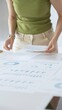 © rogerphoto - Businesswoman pointing at financial charts and graphs on a table, with a pie chart on a flip chart in the background. Business people concept