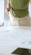© rogerphoto - Businesswoman pointing at financial charts and graphs on a table, with a pie chart on a flip chart in the background. Business people concept
