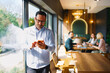 © djile - Businessman texting on smartphone while team meeting in background