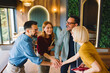 © djile - Business team stacking hands in gesture of unity and teamwork