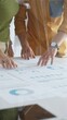 © rogerphoto - Business professionals analyzing financial reports, pointing at data points on charts and graphs lying across white desk surface