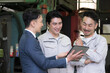 © kapinon - 工場でタブレットを使い３人で打ち合わせする作業員とビジネスマンの現場、dxやIT、AI化の機械の導入や信金ビジネスマンが借り入れ提案のイメージ