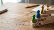 © The Stock Hub - A wooden desk with game pieces and blocks representing success, target, and goal in a modern workspace.