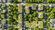 © CitraW - Aerial view of a modern residential area with green roofs and lush trees, showcasing sustainable urban living