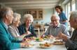 © miss irine - Elderly friends enjoy meal together in sunny community center. Seniors chat and laugh over healthy food plates. Nurse observes happy group dining and socializing. Life in retirement.