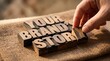 © Your Stocks  - Hand placing wooden letter blocks to spell 'your brand story' with marketing business identity narrative strategy