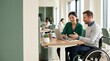 © Nexa - Professional Asian woman and Caucasian man in wheelchair collaborating on a project using a laptop in a bright, modern, inclusive office environment
