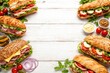 © vxnaghiyev - Variety of delicious sandwiches on a white wooden tabletop with copy space for adding text
