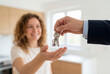 © Meow Creations - Real estate agent handing house keys to smiling woman in new home interior background