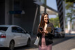 © Apichat - Young businesswoman commuting, smiling and holding smartphone