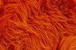 © reddish - Close up of vibrant orange artificial fur texture background with long soft shaggy fibers surface