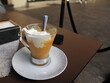© Ilarialapreziosa - Tipica granita siciliana alla pesca servita in un bicchiere di vetro con abbondante panna montata fresca, dessert estivo artigianale italiano su piattino bianco
