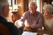 © EricMiguel - Smiling senior couple shaking hands with an advisor during a home consultation — retirement planning, estate agreement and trust signing
