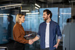 © Liubomir - Business woman and man smiling, shaking hands in a modern office, confirming a successful partnership, agreement, trust, and business cooperation, symbolizing a new venture