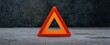© ckybe - Isolated orange warning triangle on concrete signaling potential danger or safety alert.