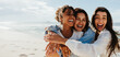 © (JLco) Julia Amaral - Three friends laughing and hugging together on a bright sunny beach
