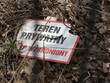 © Maciej Bonk - Zniszczona tabliczka „teren prywatny – wstęp wzbroniony” leżąca wśród suchych liści w lesie. Kontrast natury i komunikatu o zakazie dostępu