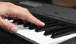 © ruangrit19 - A closeup view of a musician hand playing a melody on a modern black digital piano keyboard indoors during a music practice session for hobby.