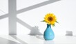 © Tahir - Bright yellow sunflower in a vibrant turquoise vase casts playful shadows on a white background.