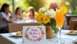 © Oleksandr - Table set for Mother Day brunch outdoors. Features a mimosa cocktail, flower bouquet, and greeting card. People dine in background, enjoying sunny day.