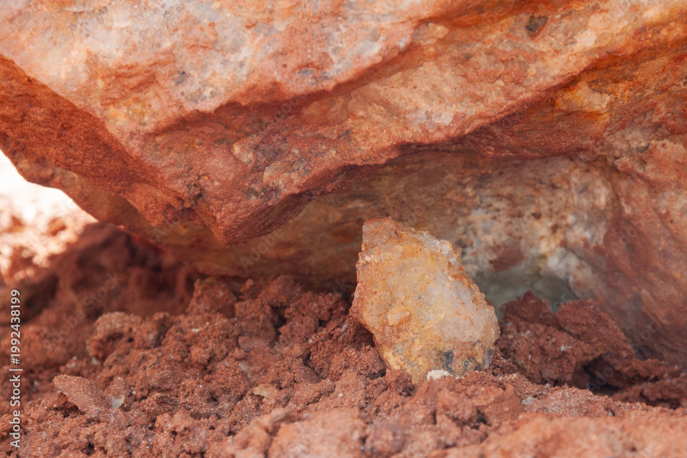 Buried In Rocks Natural quartz rock partially buried in red clay soil, showing contrast ...