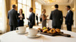 © ViskBx - Business people networking at a conference during a coffee break with pastries and coffee on a table in the foreground