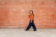 © valbar STUDIO/Stocksy - Woman Walks on Sidewalk Near Red Brick Wall