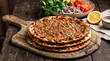 © EZD - Traditional Turkish lahmacun flatbread, Stacked minced meat pizzas on wooden board, Authentic middle eastern street food with vegetables