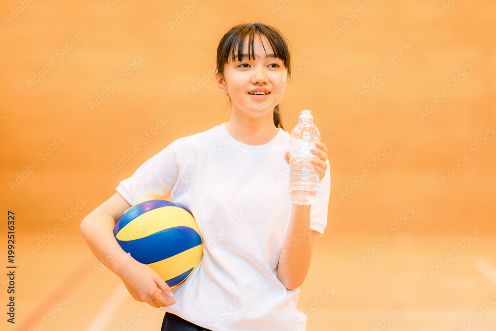 Middle school and high school girls in gym clothes playing volleyball ...